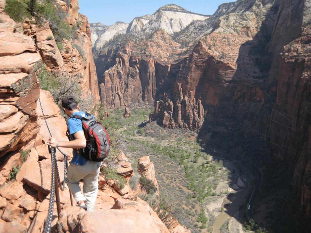 A hiker walking across a narrow stretch of angels landing hike while visiting Zion National Park.